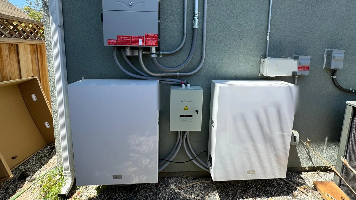 White wall-mounted battery installed beside residential electrical equipment